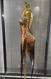 A leopard-print ballroom dance costume displayed on a mannequin torso, featuring a plunging V-neckline heavily embellished with silver rhinestones, a long sleeve, and a matching rhinestone-accented collar.