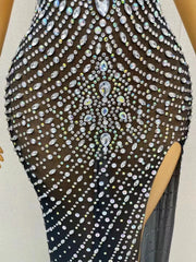 Elegant prom dress completely covered in silver rhinestones with a dramatic high split. Audre sparkling formal gown.