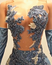 Glitter light blue prom dress with rhinestone mesh and see-through design, styled for formal events and glamorous occasions.