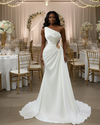 Modern one-shoulder satin wedding dress with an asymmetrical neckline, elegant draped bodice, beaded side cutout detail, and a sleek floor-length silhouette with a soft chapel-train.