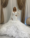 Elegant vintage mermaid wedding gown with full sleeves, pearl appliqués, and layered ruffled skirt.