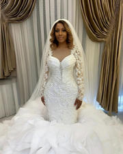 Elegant vintage mermaid wedding gown with full sleeves, pearl appliqués, and layered ruffled skirt.