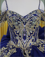 Navy blue off-shoulder quinceañera dress with gold appliqués, crystal embellishments, and full princess skirt.