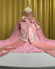 Sparkling pink quinceañera ball gown with off-shoulder sleeves, satin peplum, and glitter tulle skirt.