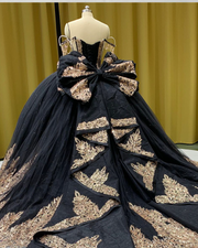 Black quinceañera dress with gold sequin appliqués, fitted bodice, and full princess skirt.