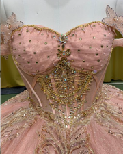 Blush pink quinceañera gown with gold beading, fitted bodice, and full princess skirt.