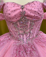 Baby pink quinceañera gown with glitter details, lace trim, and full princess ball skirt.