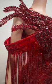 Ruby red beaded mermaid gown with sculptural chest fin details, sequin fringe off-the-shoulder sleeves, and floor-length illusion train